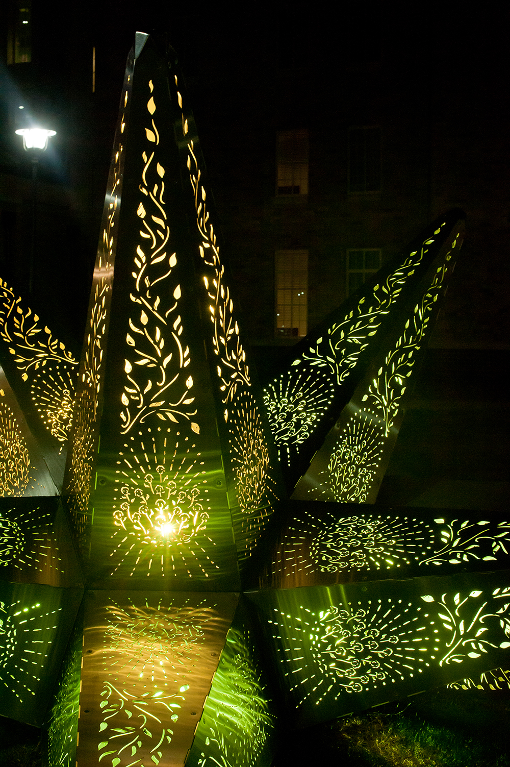 star sculpture lit up at night, yellow turning into green.
